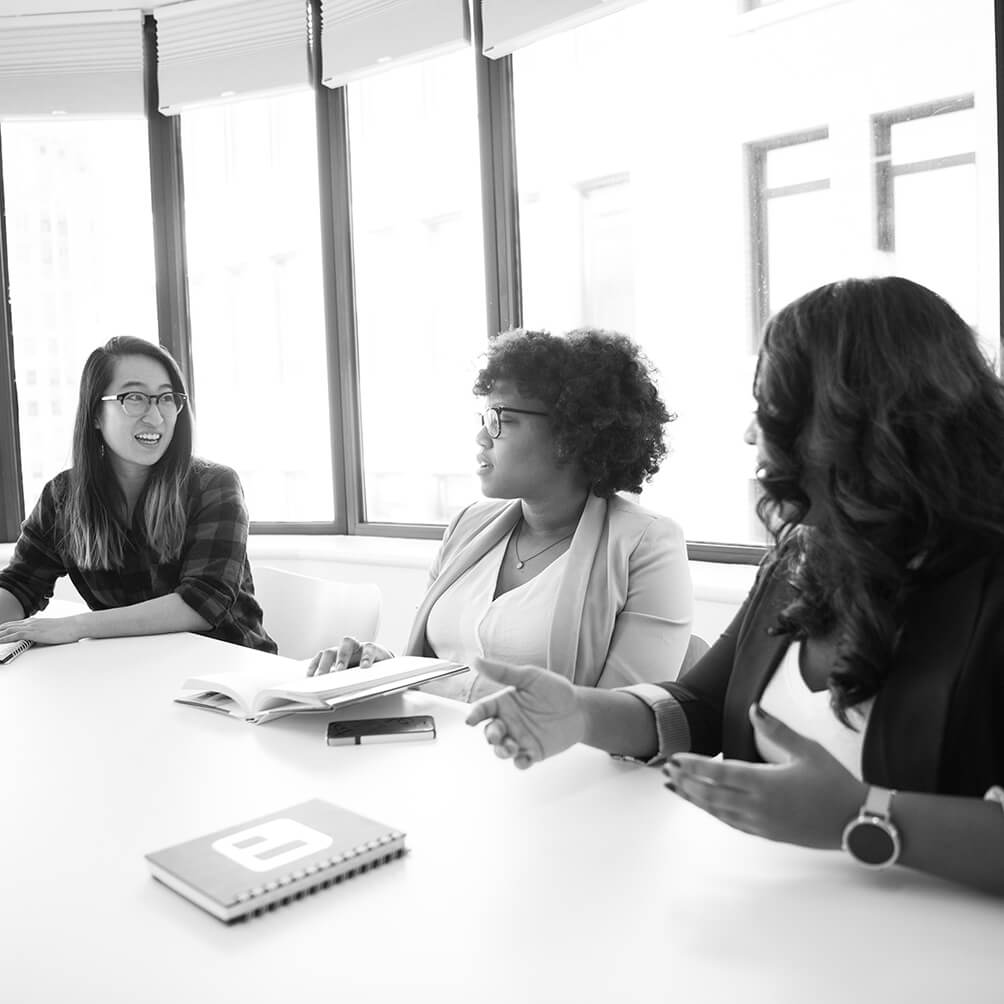 Three women talking at a conference room table